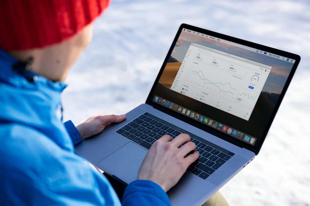Person working on a laptop analyzing charts in an outdoor setting during winter.
